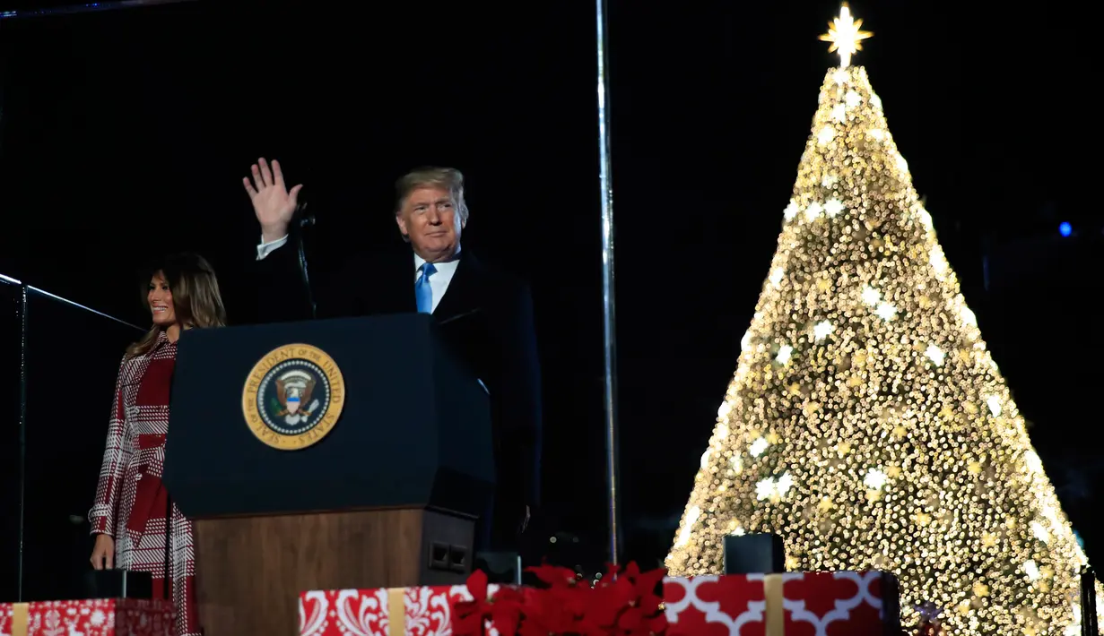 Presiden AS, Donald Trump dan ibu negara Melania Trump menghadiri upacara penerangan pohon cemara, yang menjadi Pohon Natal Nasional di taman sebelah selatan Gedung Putih, Kamis (5/12/2019). Pohon cemara setinggi 30 kaki tersebut dihiasi 50.000 lampu dan 450 bintang. (AP/Manuel Balce Ceneta)