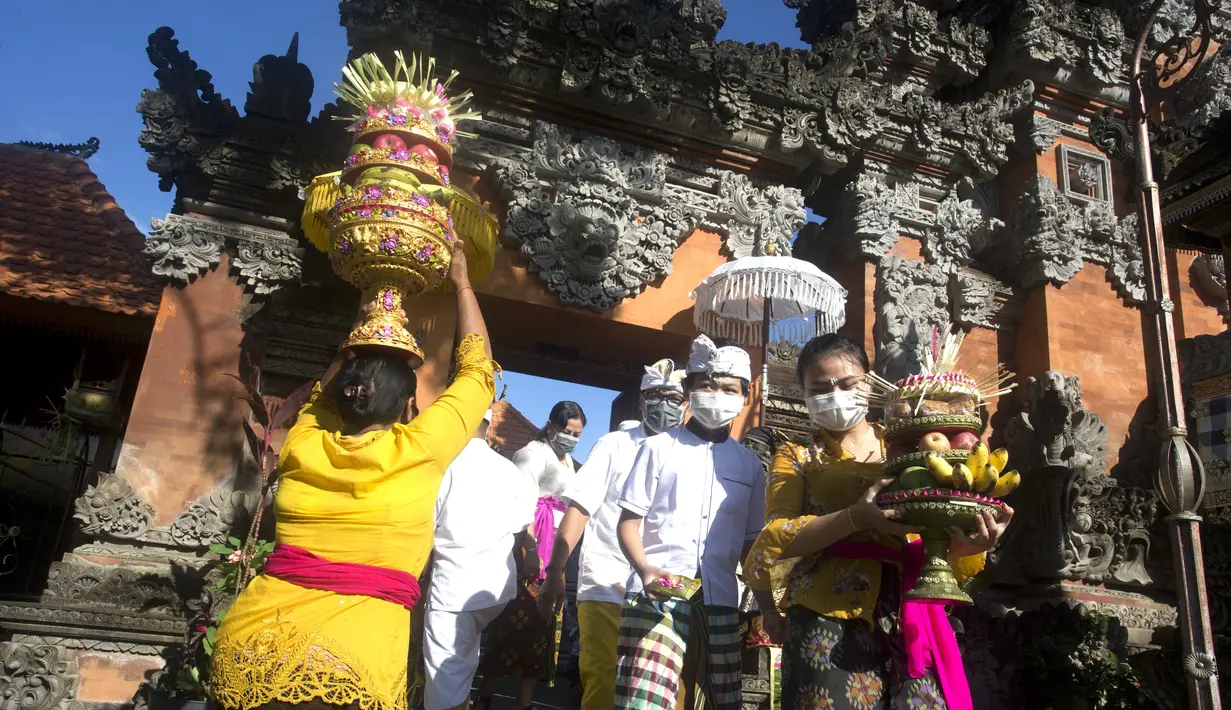 Umat Hindu membawa sesajen saat Hari Raya Galungan di sebuah pura di Bali, Rabu (14/4/2021). Perayaan Hari Raya Galungan yang merupakan hari kemenangan kebenaran (Dharma) atas kejahatan (Adharma) itu diikuti umat Hindu di Bali dengan menerapkan protokol kesehatan. (AP/Firdia Lisnawati)