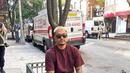 Duduk santai di pinggir jalan kota New York, UUS tampil kasual mengenakan kaos polos Erigo dipadu celana jeans dan high up sneakers berwarna coklat. (Instagram/uusbiasaaja).