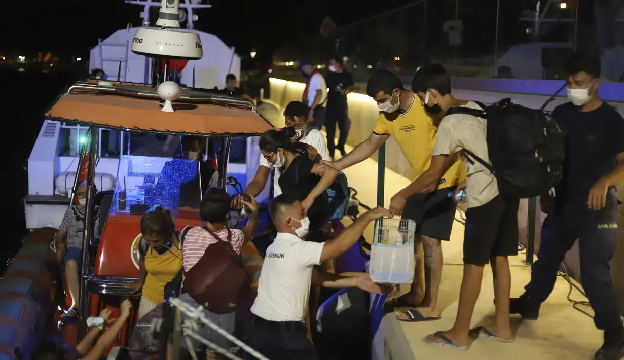 Orang-orang menunggu untuk dievakuasi dengan perahu setelah kebakaran hutan mencapai Pembangkit Listrik Kemerkoy di Milas di barat daya Turki, Rabu (4/8/2021) malam. (AP Photo/Cem Tekkesoglu)