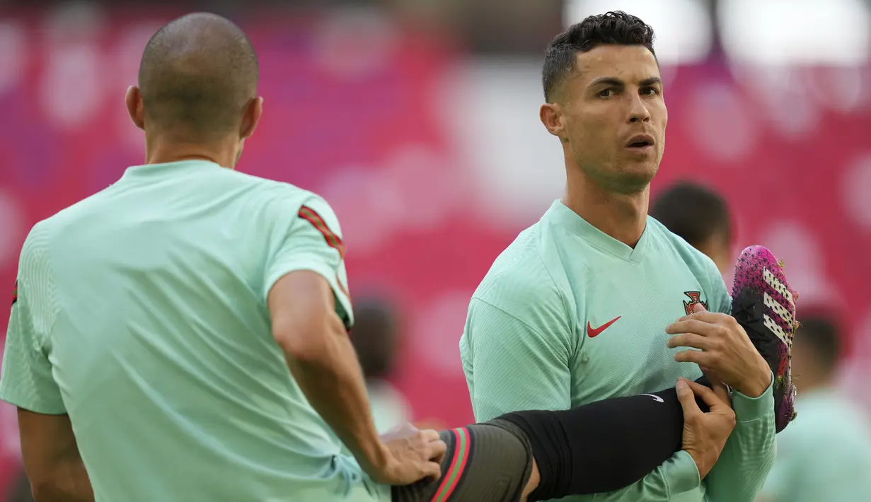 Penyerang Portugal, Cristiano Ronaldo berdiri di samping rekan setimnya Pepe selama sesi latihan di arena stadium di Munich, Jumat (18/6/2021). Portugal akan bertanding melawan Jerman pada grup F Euro 2020 di Allianz Arena. (AP Photo/Matthias Schrader)