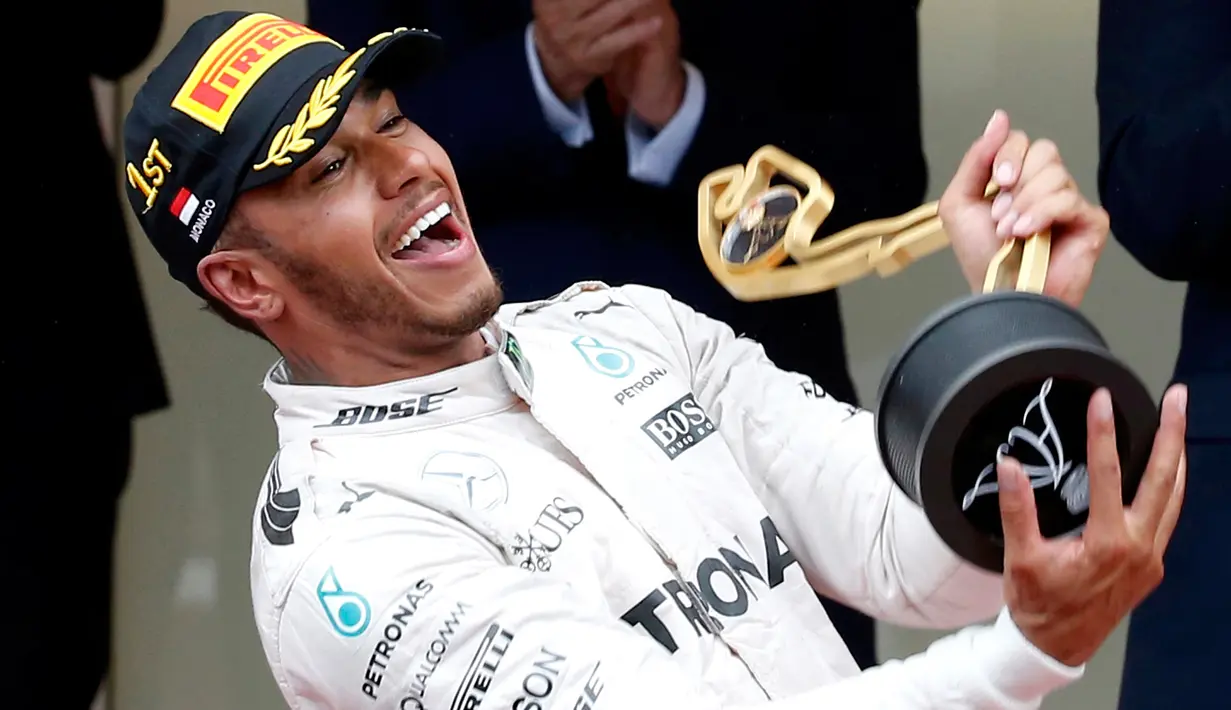 Pemabalap Mercedes Lewis Hamilton memegang pialanya diatas podium usai berhasil menjuarai Grand Prix di Monaco, (29/5). Hamilton menjadi yang tercepat dengan mencatatkan waktu satu jam 59 menit 29,133 detik. (REUTERS/Eric Gaillard)