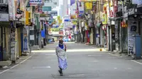 Seorang pria berjalan di sepanjang jalan yang sepi selama penguncian nasional untuk mengekang penyebaran virus corona Covid-19 di Kolombo, Sri Lanka (21/8/2021). rata kasus harian Covid-19 di Sri Lanka kini mencapai 4.792 orang, melonjak lebih dari dua kali lipat dalam sebulan terakhir. (AFP/Ishara