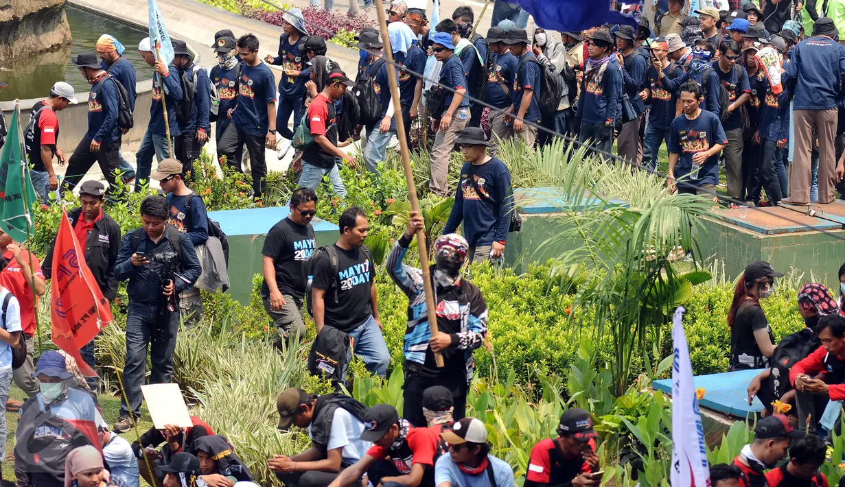 Massa buruh melintasi taman pembatas jalan di sekitar Kawasan Patung Patung Arjuna Wiwaha saat aksi perayaan hari Buruh Internasional 2017 di Jakarta, Senin (5/1). Ribuan massa buruh ikut turun ke jalan. (Liputan6.com/Helmi Fithriansyah)