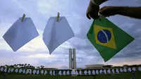 Sapu tangan putih yang mewakili warga Brasil yang meninggal karena COVID-19 digantung di atas lapangan untuk memprotes kebijakan kesehatan pemerintah di luar Kongres Nasional, Brasilia, Senin (18/10/2021). Brasil pada 8 Oktober melampaui 600.000 kematian akibat virus corona. (AP Photo/Eraldo Peres)