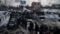 Warga Ukraina melintasi jalan darurat di bawah jembatan yang hancur saat melarikan diri dari Irpin di pinggiran Kiev, Ukraina, 8 Maret 2022. Tahun kedua perang, Rusia-Ukraina sama-sama mempersiapkan serangan besar-besaran dengan merekrut puluhan ribu tentara dan mengirim mereka ke garis depan. (AP Photo/Felipe Dana, File)