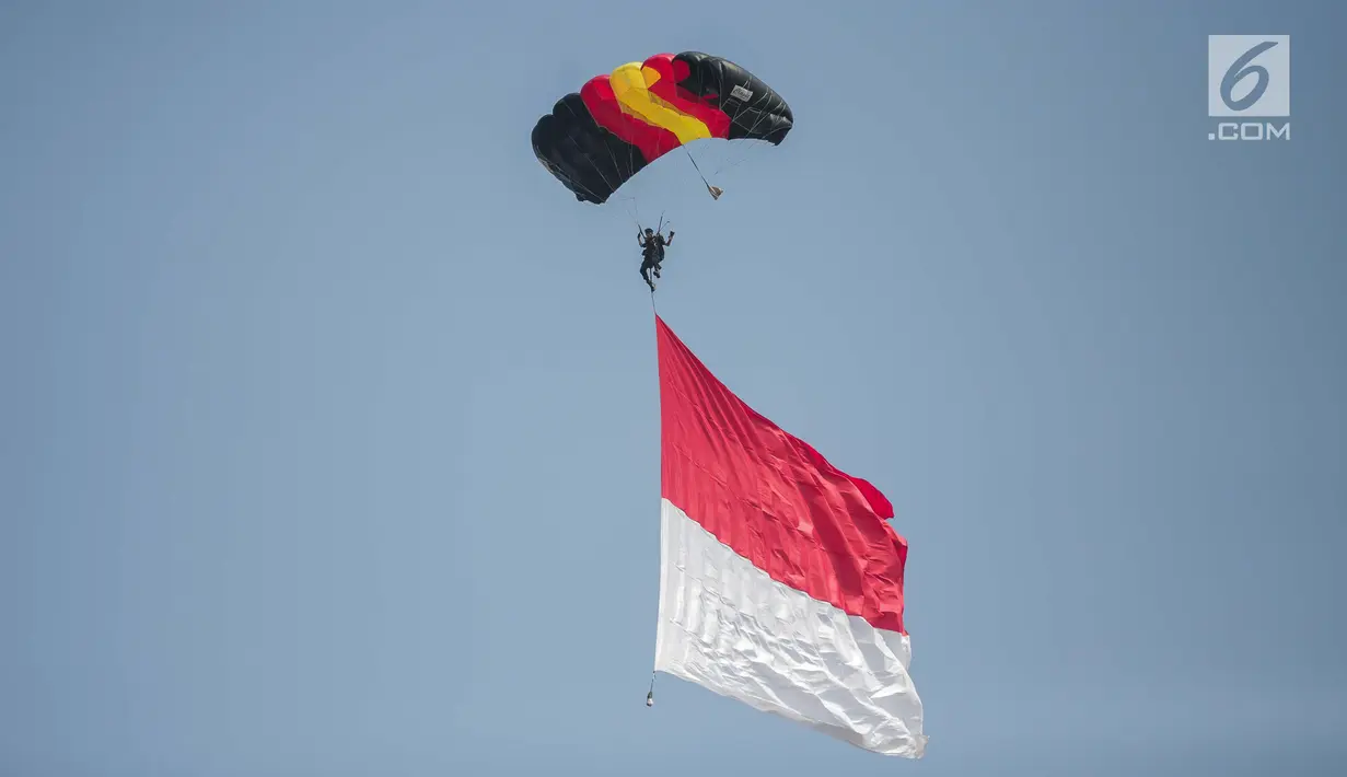 Penerjun payung membawa bendera Merah Putih saat perayaan HUT ke-73 Bhayangkara di Monas, Jakarta, Rabu (10/7/2019). Sebanyak 22 penerjun payung dari TNI dan Polri ikut menyemarakkan HUT ke-73 Bhayangkara. (Liputan6.com/Faizal Fanani)