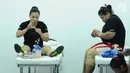 Lifter putri Dewi Safitri (kiri) dan Nurul Akmal memasang ikatan pelindung jari jelang melakukan angkatan pada tes prestasi pelatnas angkat besi Asian Games 2018 di Mako Lanmar Jakarta, Selasa (6/3). (Liputan6.com/Helmi Fithriansyah)