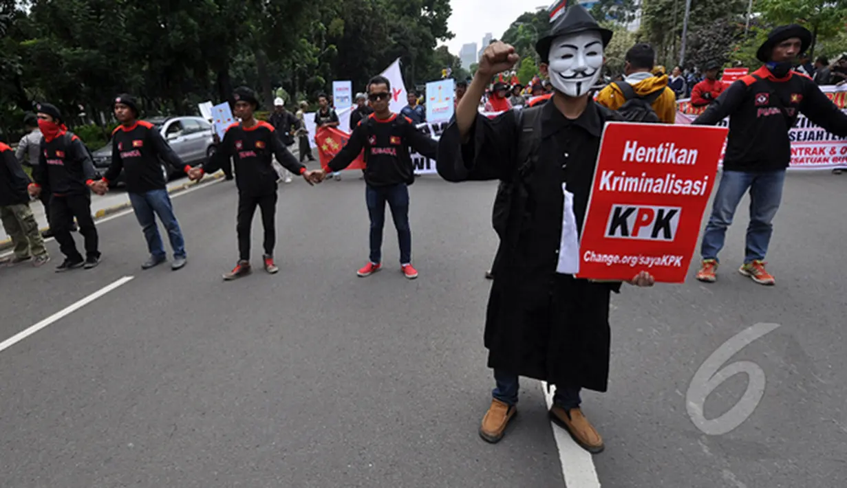 Seorang demonstran mengenakan topeng berjalan membawa poster saat aksi 100 Hari Pemerintahan Joko Widodo-Jusuf Kalla di depan Istana Negara, Jakarta, Rabu (28/1/2015). (Liputan6.com/Miftahul Hayat)