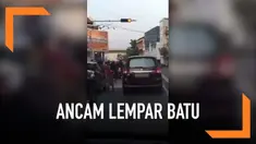 Sambil membawa batu besar, seorang pria menghampiri sejumlah pengendara yang berhenti saat lampu merah. Pria tersebut mengancam melempar batu jika tak diberi uang.