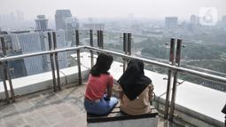 Warga menyaksikan saat polusi menyelimuti langit Jakarta, Senin (20/6/2022). Angka ini menjadikan DKI Jakarta kembali menempati ranking pertama kualitas udara terburuk di dunia disusul Santiago, Cile dengan AQI US, 180 dan Dubai Uni Emirat Arab AQI US 161. (merdeka.com/Iqbal S. Nugroho)