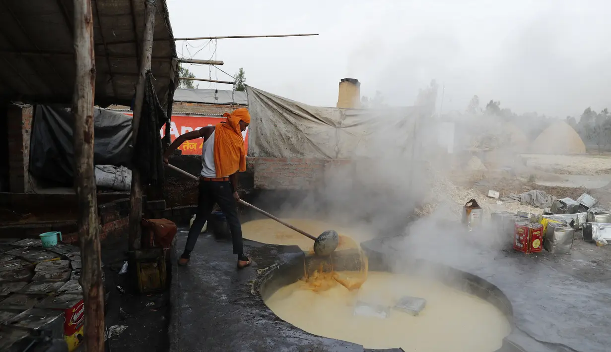 Seorang pekerja mengaduk jus tebu untuk membuat gula merah di pinggiran Bareilly, India, Selasa (23/3/2021).  Jaggery adalah gula tradisional yang tidak dimurnikan yang dikonsumsi di banyak bagian Asia, terbuat dari molase tebu dan nira kurma. (AP Photo/Rajesh Kumar Singh)