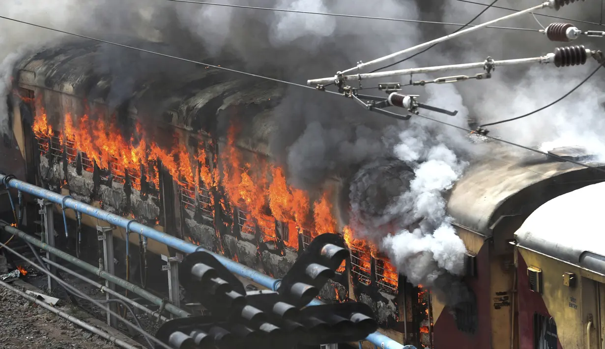Kobaran Api melahap kereta api yang dibakar pengunjuk rasa di stasiun kereta api Secunderabad di Hyderabad, India, Jumat (17/6/2022). Hampir 500 pengunjuk rasa jauh melebihi jumlah polisi saat mereka mengamuk selama lebih dari satu jam di stasiun kereta api Secundrabad di India selatan. (AP Photo/Mahesh Kumar A)