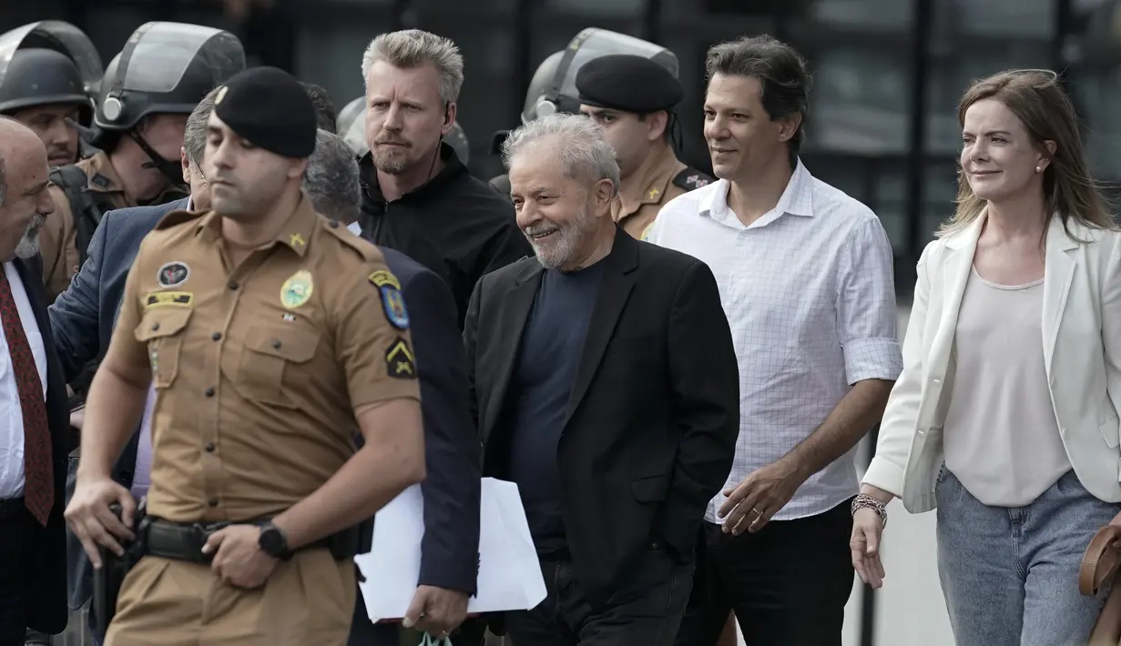 Mantan Presiden Brasil Luiz Inacio Lula da Silva (tengah) tersenyum ketika berjalan keluar dari markas Polisi Federal setelah dipenjara atas tuduhan korupsi di Curitiba, Brasil, (8/11/2019). Luiz Inácio Lula da Silva telah dibebaskan setelah lebih dari 18 bulan dipenjara. (AP Photo/Leo Correa)