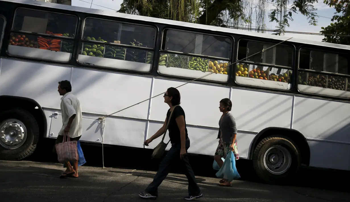 Warga berjalan melintas di depan pasar bus 'Sacolao' di Santa Teresa di Rio de Janeiro, Brasil, Selasa (7/7/2015). Pasar bus ini menjual sayur dan buah-buahan dengan harga yang terjangkau. (REUTERS/Pilar Olivares)