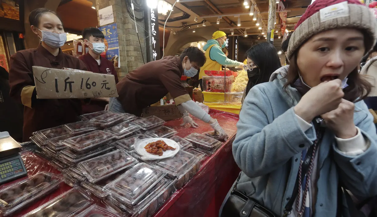 Pengunjung mencicipi jajanan kering di pasar Jalan Dihua di Taipei, Taiwan, Jumat, 20 Januari 2023. Pembeli Taiwan mulai berburu makanan lezat, jajanan kering, dan barang murah lainnya di pasar menjelang perayaan Tahun Baru Imlek yang menurut kalender lunar akan berlangsung pada 22 Januari. (AP Photo/Chiang Ying-ying)