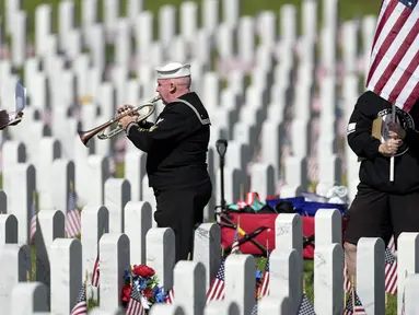 Pensiunan Angkatan Laut Amerika Serikat Yeoman Mark Stallins memainkan Taps untuk keluarga prajurit yang gugur di sebuah kuburan di Pemakaman Nasional Fort Logan, Sheridan, Colorado, Amerika Serikat, 30 Mei 2022. (AP Photo/David Zalubowski)