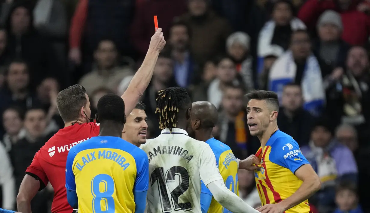 Pemain Valencia, Gabriel Paulista menerima kartu merah dari wasit Javier Alberola Rojas saat bertanding melawan Real Madrid  selama pertandingan La Liga Spanyol di stadion Santiago Bernabeu di Madrid, Jumat (3/2/2023). Valencia kini tertahan di urutan 14 dengan 20 poin. (AP/Bernat Armangue)