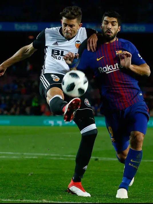 Pemain Barcelona, Luis Suarez berebut bola dengan pemain Valencia, Gabriel Paulista pada semifinal pertama Copa del Rey di Stadion Camp Nou, Jumat (2/2). Menang 1-0, peluang Barcelona untuk melaju ke partai final terbuka lebar. (AP/Manu Fernandez)