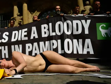 Aktivis yang bertelanjang dada berbaring di jalan saat menggelar protes terhadap adu banteng di Pamplona, Spanyol, Jumat (5/7/2019). Aksi protes ini digelar sehari sebelum pembukaan Festival San Fermin. (AP Photo/Alvaro Barrientos)