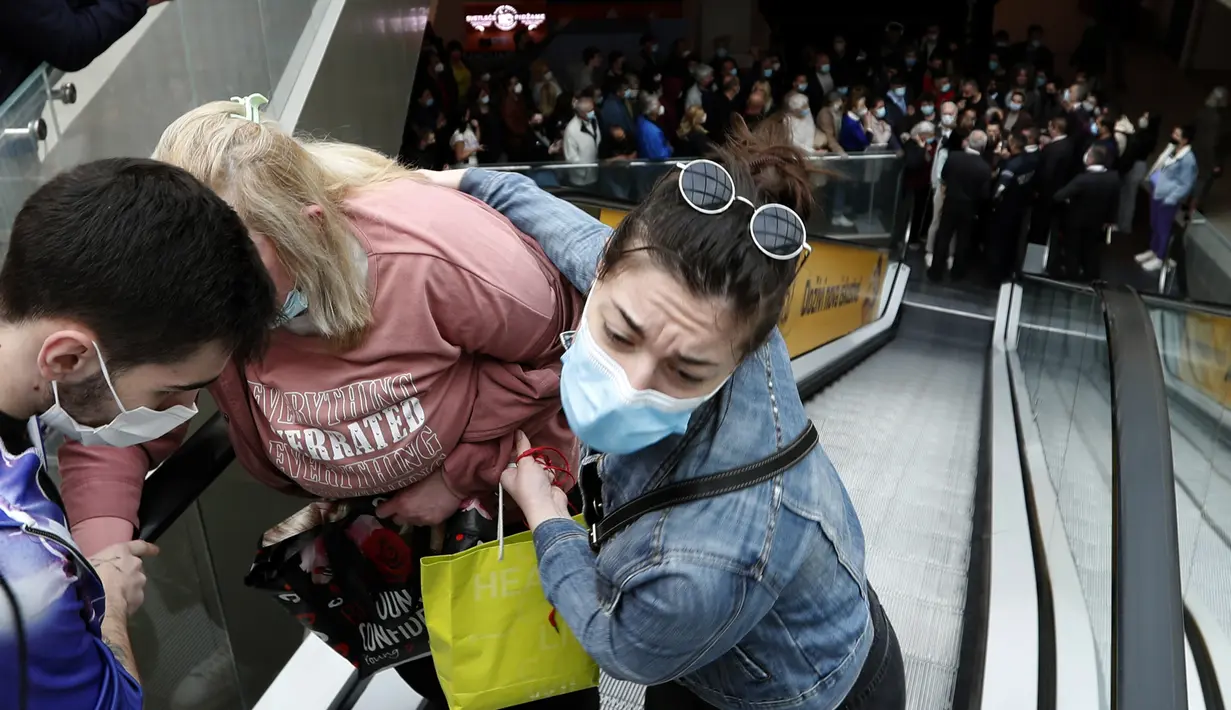 Seorang wanita dibantu naik eskalator saat orang antre vaksinasi dan menjadi salah satu orang yang menerima kupon belanja, di pusat perbelanjaan Usce di Beograd, Kamis (6/5/2021). Pemerintah Serbia menawarkan uang Rp 430 ribu bagi warganya yang divaksinasi sebelum akhir Mei. (AP/Darko Vojinovic)