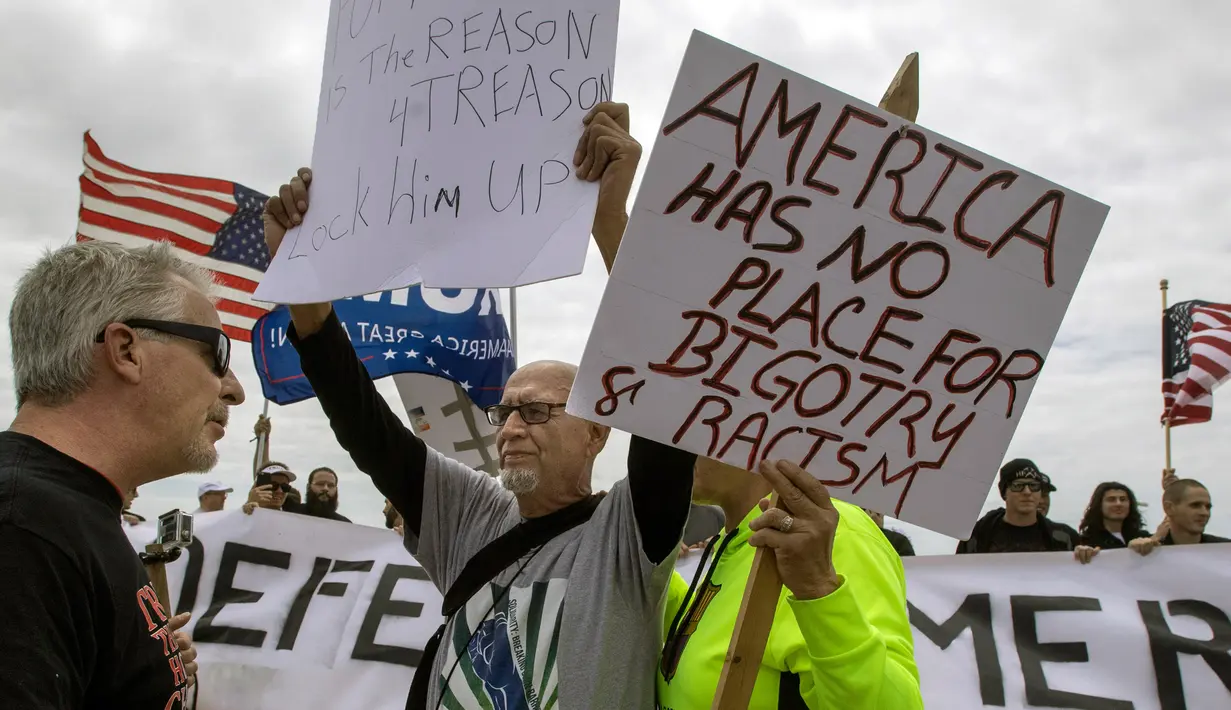 Pendukung Presiden Donald Trump berhadapan dengan pengunjuk rasa anti-Trump yang membawa poster saat menggelar aksinya di Huntington Beach, California (25/3). (Mindy Schauer / The Orange County Register via AP)