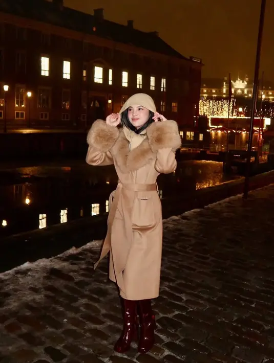 Di Copenhagen, Lyodra mengenakan long coat dengan aksen bulu di leher dan lengan. Dipadukan Inner hoodie coklat dan sepatu bootsnya. [@lyodraofficial]