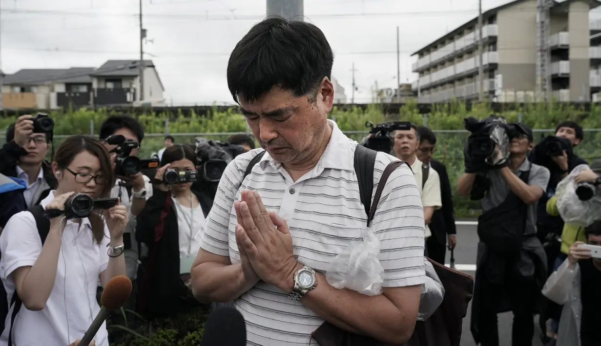 Seorang pria berdoa untuk para korban setelah meletakkan bunga di luar gedung Kyoto Animation Studio di Kyoto, Jepang (19/7/2019). Stasiun televisi NHK melapor, seorang pria yang menuangkan bensin ke sekitar gedung animasi telah ditahan. (AP Photo/Jae C. Hong)