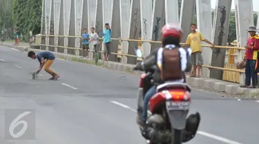 Seorang bocah mengambil uang yang dilempar pengguna jalan di Jembatan Cikalong, Jawa Barat, Sabtu (2/7). Memasuki mudik Lebaran, jumlah pencari uang sedekah di kawasan itu meningkat dibanding hari biasa (Liputan6.com/Gempur M Surya)