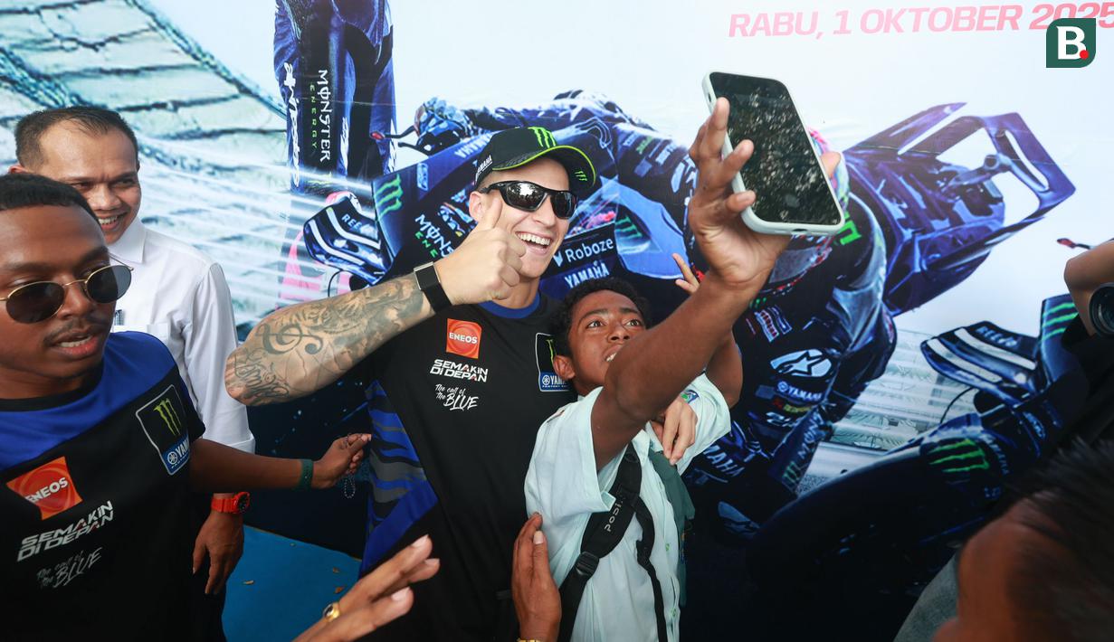 Pembalap Monster Energy Yamaha, Fabio Quartararo, foto bersama siswa saat mengunjungi SMAN 2 Mataram, Nusa Tenggara Barat (NTB), Rabu (1/10/2025). (Bola.com/M Iqbal Ichsan)