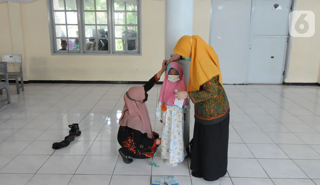 Guru melakukan pengukuran tinggi dan berat badan  murid kelas 1  saat kegiatan Bulan Imunisasi Anak Sekolah (BIAS) di SDI Al-Hidayah, Depok, Jawa Barat, Kamis (18/11/2021).  Sebanyak 100.719 siswa kelas I, II, dan V SD atau MI sederajat menjadi sasaran pemberian imunisasi. (merdeka.com/Arie Basuki)