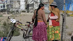 Seorang peserta berbincang dengan ibunya sebelum balapan sepeda Cholita dimulai di El Alto, La Paz, Bolivia (29/10). Peserta yang ikut wajib menggunakan rok tradisional setempat dan mengikat kepang rambut mereka. (Reuters/David Mercado)