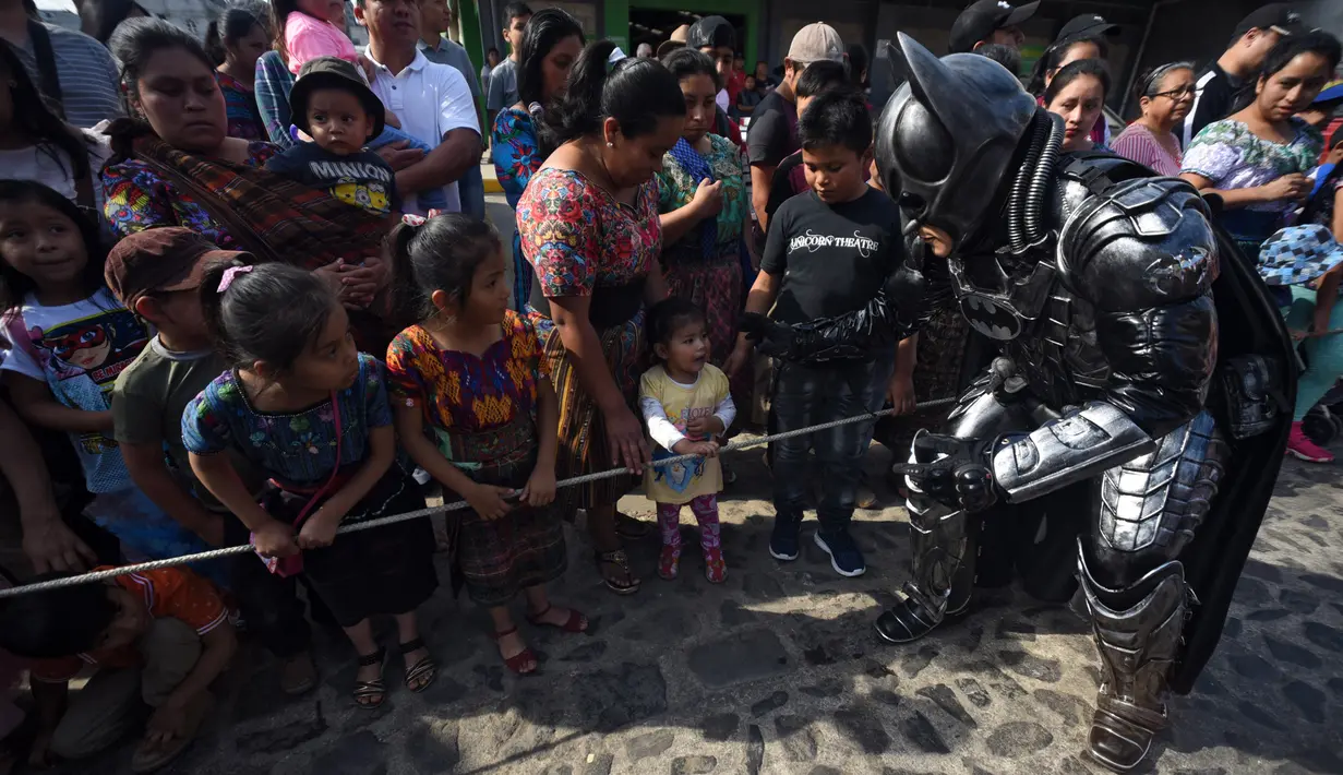Anggota Saturno Club mengenakan kostum Batman menyapa anak-anak selama parade Dance of Costumes tahunan di sepanjang jalan kota Sumpango, Guatemala, Senin (30/12/2019). Parade kostum yang menampilkan karakter televisi dan film ini untuk memeriahkan malam pergantian tahun. (ORLANDO ESTRADA/AFP)