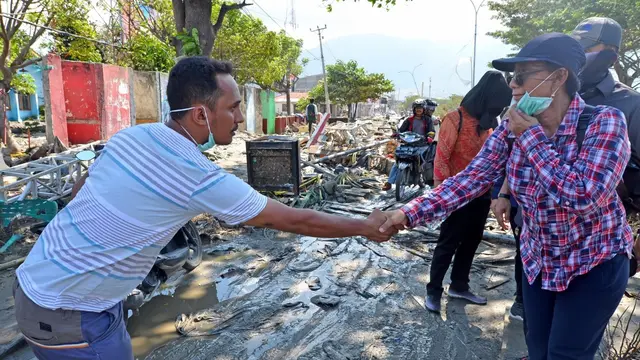 Menteri Kelautan dan Perikanan Susi Pudjiastuti bersalaman dengan salah seorang warga di sekitar lokasi rerutuhan bangunan. (Istimewa)
