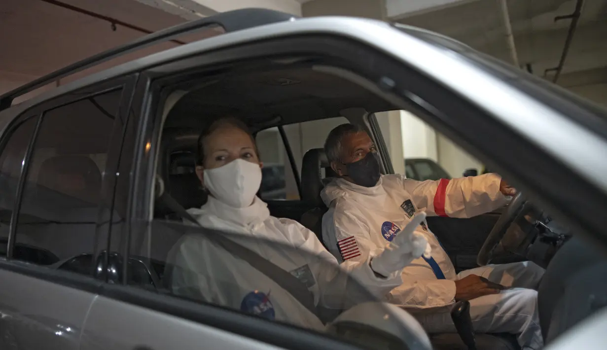Akuntan Brasil Tercio Galdino (66) dan istrinya Alicea Galdino mengenakan pakaian pelindung mirip astronaut saat mengendarai mobil menuju Pantai Copacabana di Rio de Janeiro, Brasil, 12 Juli 2020. (Mauro Pimentel/AFP)