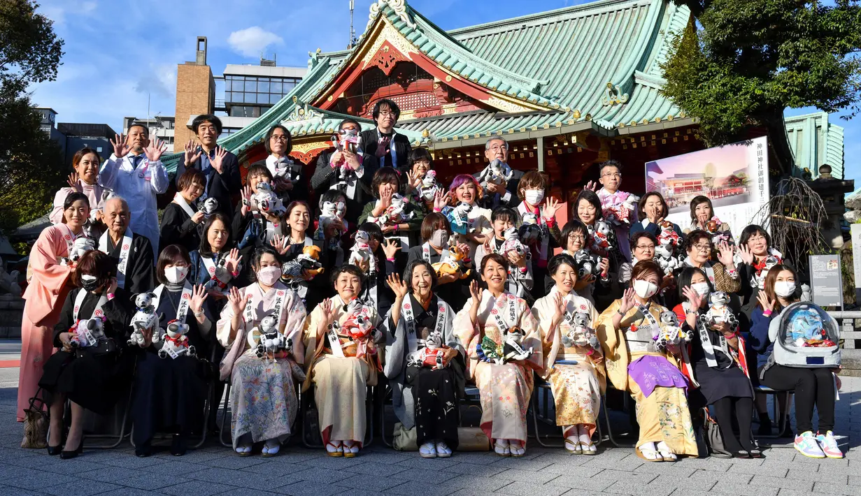 Pemilik robot peliharaan Sony Aibo berpose untuk foto kenang-kenangan dalam acara perayaan ulang tahun ketiga Aibo dan berharap kesehatan yang baik pada masa depan di Kuil Kanda, Tokyo, Jepang, Jumat (12/11/2021). (Kazuhiro NOGI/AFP)