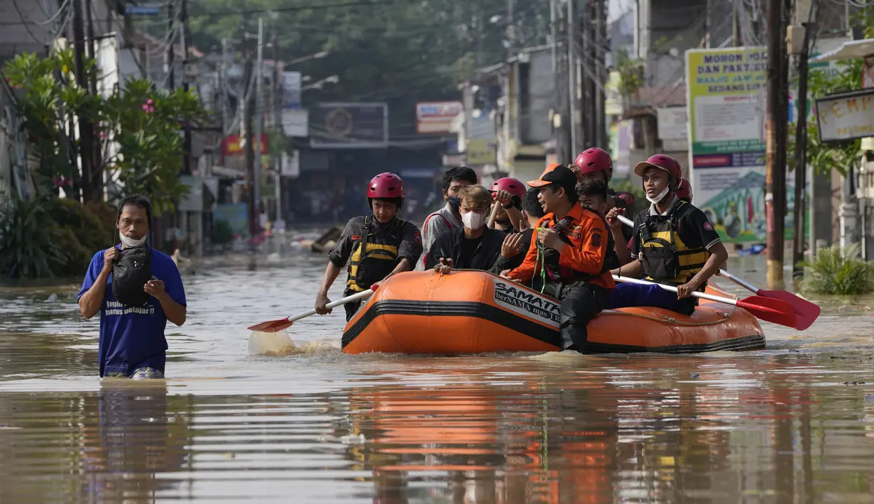 Warga duduk dalam perahu karet saat mereka mengungsi ke tempat yang lebih tinggi selama banjir di Bekasi, Jawa Barat, Kamis (17/2/2022). Hujan deras yang dikombinasikan dengan perencanaan pembuangan limbah kota yang buruk sering menyebabkan banjir besar. (AP Photo/Achmad Ibrahim)