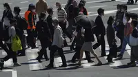 Orang-orang mengenakan masker untuk membantu mencegah penyebaran virus corona berjalan di sepanjang penyeberangan pejalan kaki di Tokyo (21/4/2021). Ibukota Jepang mengonfirmasi lebih dari 840 kasus virus corona baru pada hari Rabu. (AP Photo/Eugene Hoshiko)