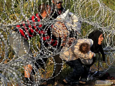 Imigran Suriah berusaha melewati pagar berduri di wilayah Hungaria dekat perbatasan Serbia, wilayah Roszke, Kamis (27/8/2015). Pemerintah Hungaria berencana untuk memperketat perbatasan bagian selatannya dari para pengungsi. (REUTERS/Bernadett Szabo)