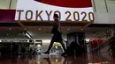Seorang pramugari berjalan di depan layar besar Olimpiade Tokyo 2020 di Bandara Internasional Narita, Tokyo, Kamis (15/7/2021). Upacara pembukaan Olimpiade Tokyo akan digelar pada 23 Juli 2021 dan berakhir pada 8 Agustus 2021. (AP Photo/Kiichiro Sato)