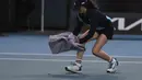 Seorang ball girl berusaha menangkap seekor serangga yang memasuki lapangan menggunakan handuk ketika laga Australia Open 2024 antara petenis Inggris, Emma Raducanu melawan petenis Amerika Serikat di Melbourne Park, Melbourne, Australia, Selasa (16/01/2024). (AP Photo/Louise Delmotte)