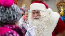Seorang pria berpakaian Santa Claus berbicara dengan seorang anak di kantor pos desa Himmelpfort, Jerman, (10/11/2015). Lebih dari ribuan surat telah diterima oleh Deutsche Post. (REUTERS/Hannibal Hanschke)
