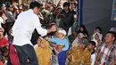 Presiden Joko Widodo atau Jokowi membagikan buku kepada seorang anak saat mengunjungi korban gempa di Desa Madayin, Sambelia, Lombok Timur, NTB, Senin (30/7). (Agus Suparto/Indonesian Presidential Palace/AFP)