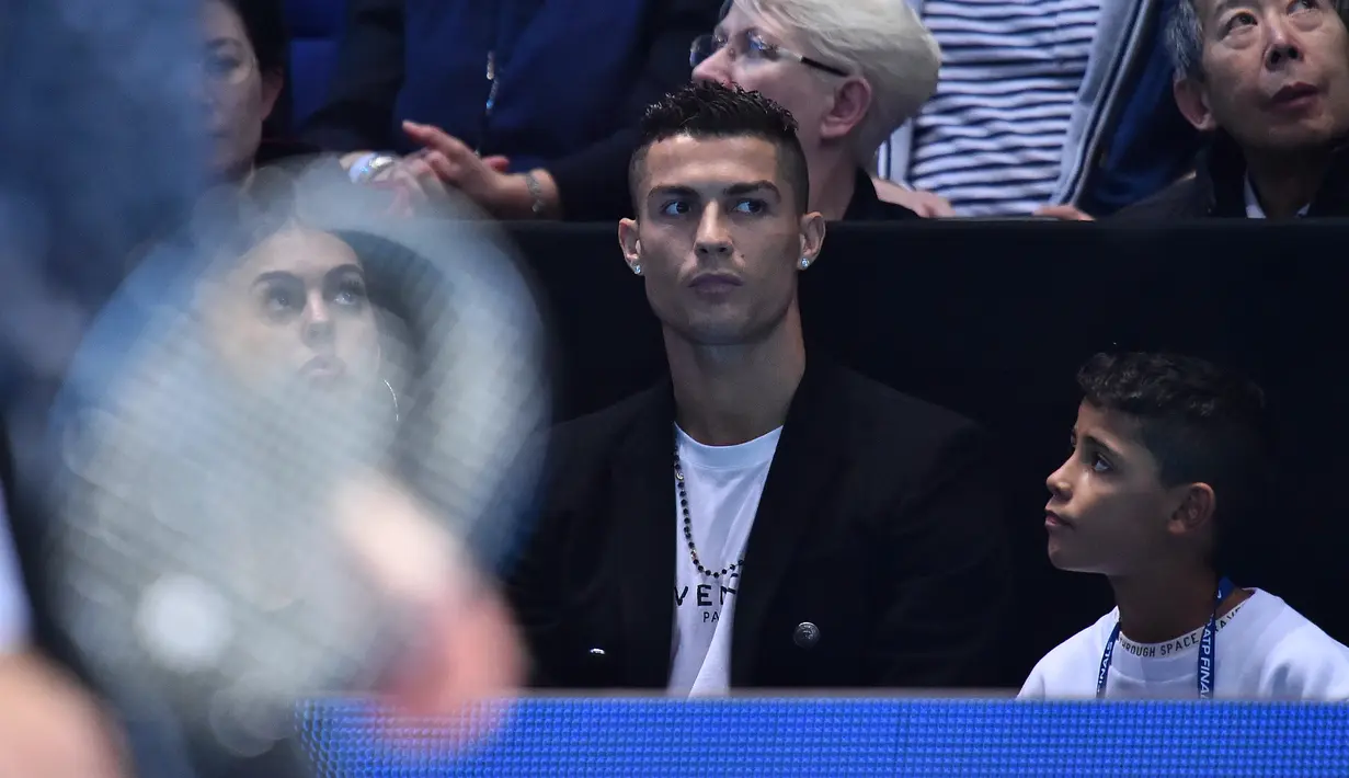 Cristiano Ronaldo bersama sang kekasih, Georgina Rodriguez dan anaknya, Cristiano Jr menyaksikan petenis Serbia, Novak Djokovic menghadapi John Isner dari AS pada laga tenis dunia, ATP Finals 2018, di O2 Arena, London, Senin (12/11). (Glyn KIRK/AFP)