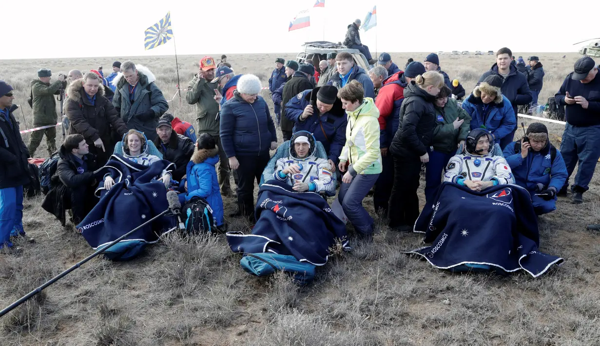 Astronot AS Kate Rubins, kosmonot Rusia Anatoly Ivanishin, dan astronot Jepang Takuya Onishi beristirahat setelah berhasil mendarat di daerah terpencil sekitar 150 km sebelah tenggara dari Dzhezkazgan, Kazakhstan (30/10). (Reuters/Dmitri Lovetsky)