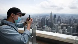 Seorang turis dengan mengenakan masker mengambil gambar dari dek obseravsi di Menara Kuala Lumpur di Kuala Lumpur, Rabu (1/7/2020). Malaysia memasuki pelonggaran Perintah Kontrol Gerakan (MCO) setelah tiga bulan pembatasan karena virus corona Covid-19. (AP Photo/Vincent Thian)