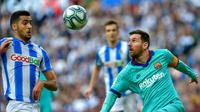 Penyerang Barcelona, Lionel Messi, saat berusaha melewati hadangan gelandang Real Sociedad, Mikel Merino, pada laga pekan ke-17 La Liga Spanyol di Reale Arena, Sabtu (14/12/2019). (AFP/Ander Gillenea)