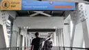 Petugas memeriksa suhu calon penumpang di jembatan penghubung atau Skybridge antara halte Transjakarta dan Stasiun LRT Velodrome, Jakarta, Minggu (1/11/2020). (merdeka.com/Iqbal S. Nugroho)