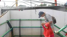 Pejalan kaki melintasi jembatan penyeberangan orang yang terhalang instalasi kabel di Depok, Jawa Barat, Sabtu (8/12). Selain mengganggu kenyamanan, keberadaan instalasi kabel semrawut tersebut membahayakan pejalan kaki. (Liputan6.com/Immanuel Antonius)