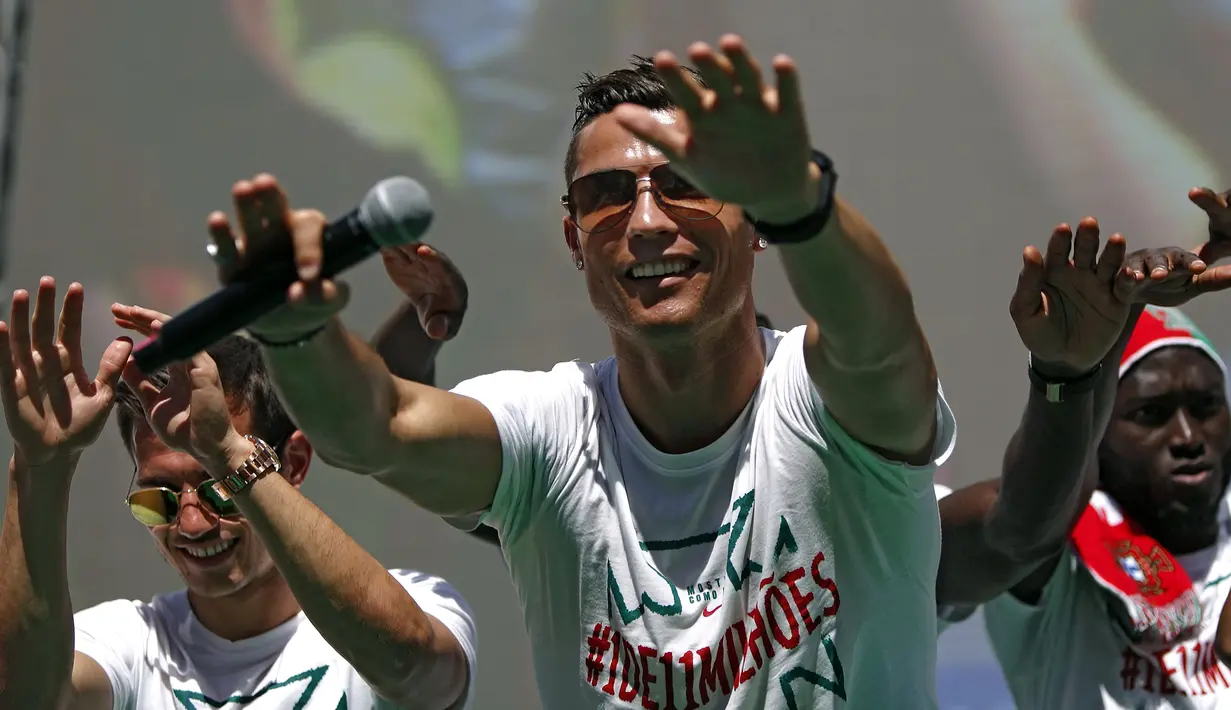 Cristiano Ronaldo dan tim kesebelasan menyapa pendukung mereka di atas bus terbuka saat kembali ke Lisbon, Portugal, Senin (11/7). Portugal menjadi juara Piala Eropa 2016 usai mengalahkan Prancis di final. (REUTERS / Pedro Nunes)